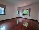 Spacious bedroom with glossy hardwood floors and ample natural light