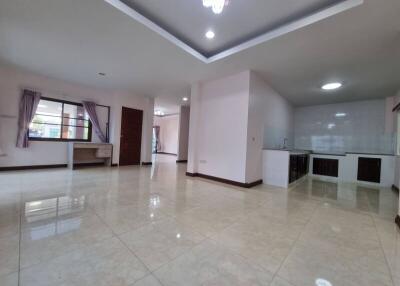 Spacious living room with attached open kitchen, large windows, and tiled flooring
