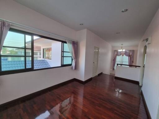 Spacious living room with large windows and polished wooden flooring