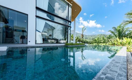 Luxurious outdoor pool with a view of a modern house and lush greenery