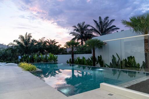 Luxurious pool area with tropical landscaping and sunset view
