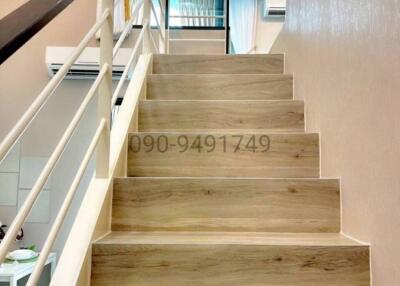 Modern wooden staircase leading to upper floor with reflective glass balustrade