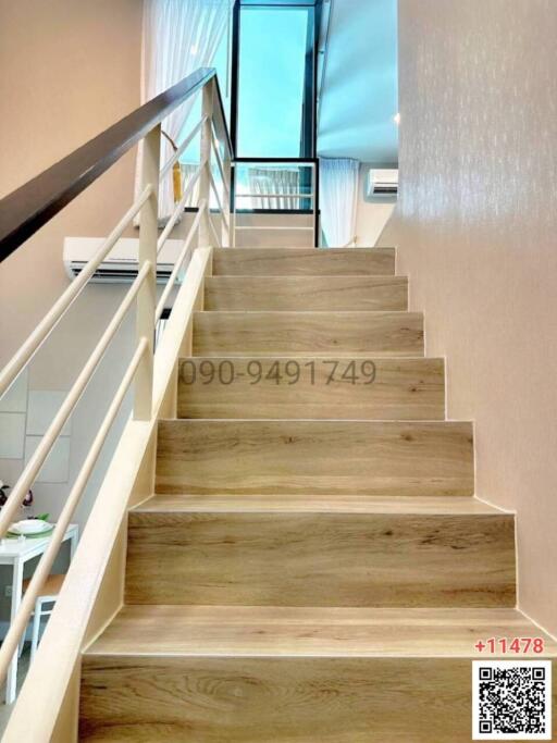 Modern wooden staircase leading to upper floor with reflective glass balustrade