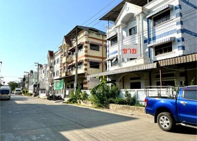 Street view of a multi-level residential building with parked vehicles