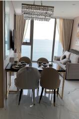 Elegant living room with ocean view, marble flooring, and modern chandelier