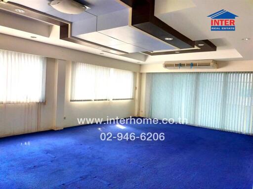 Spacious living room with large windows and blue carpet