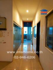 Long narrow hallway in a residential building with multiple doors and glass panels