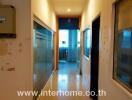 Long narrow hallway in a residential building with multiple doors and glass panels