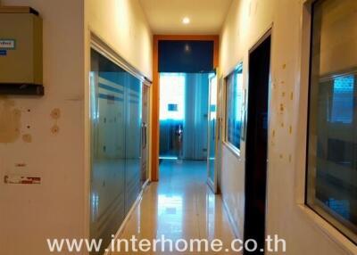 Long narrow hallway in a residential building with multiple doors and glass panels