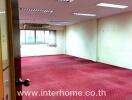 Spacious commercial office space with red carpet and fluorescent lighting
