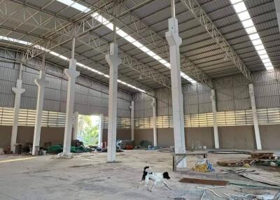 Spacious industrial warehouse interior with high ceiling and construction debris