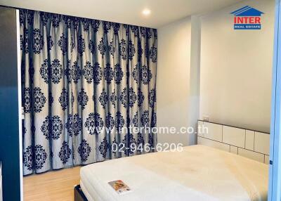 Spacious modern bedroom with large patterned curtains and a comfortable bed