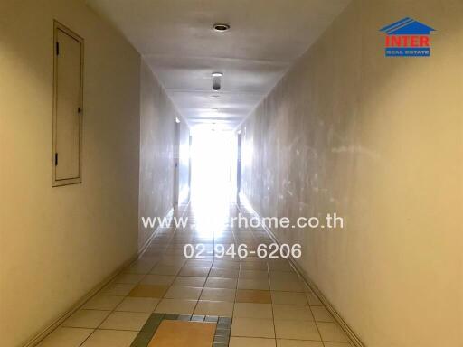 Brightly lit corridor in residential building featuring tiled floor and white walls