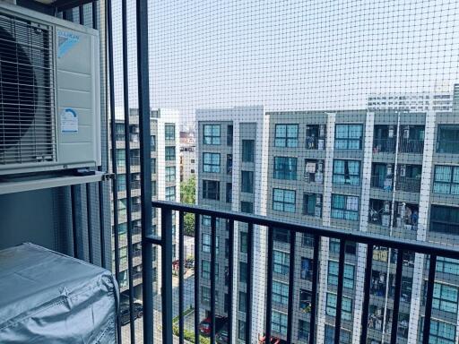Urban apartment balcony view with air conditioning unit and protective mesh