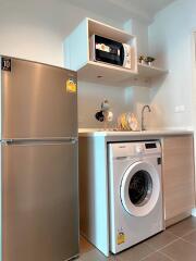 Compact kitchen space showcasing modern appliances including a refrigerator, microwave, and washing machine
