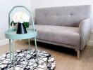 Modern living room with grey sofa, stylish marble pattern rug, and mint side table with a vase of white flowers