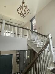 Elegant interior view of a building featuring a chandelier, staircase, and upper balcony
