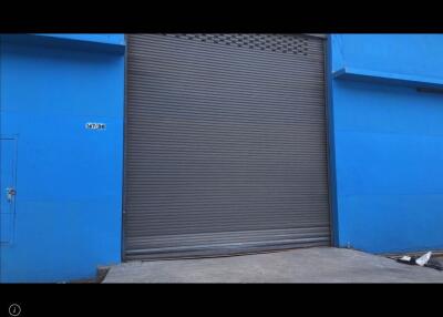 Exterior view of a blue industrial building with a large gray metal shutter