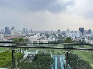 Expansive city view from a high-rise balcony overlooking a swimming pool and golf course