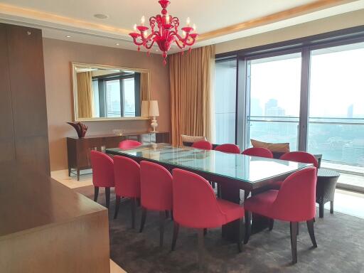 Elegant dining room with red chairs and a glass table overlooking city views