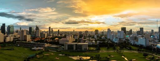 Panoramic view of a sprawling city at sunset with skyscrapers and green spaces