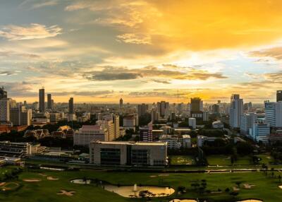 Panoramic view of a sprawling city at sunset with skyscrapers and green spaces