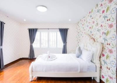 Spacious and bright bedroom with floral wallpaper and modern furnishings