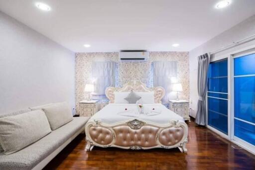 Elegant bedroom with modern and classic design elements, featuring a large bed, wooden flooring, and blue accents