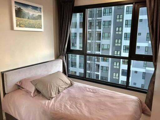 Cozy bedroom with large window view of city buildings