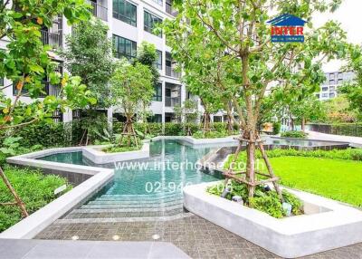 Luxurious outdoor swimming pool area with lush greenery in a modern residential complex