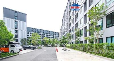 Modern residential apartment exterior with parked vehicles and lush greenery