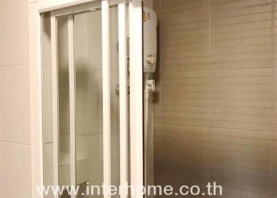 Compact bathroom with enclosed shower and mounted water heater