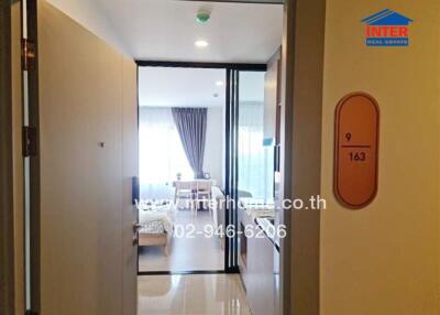 View into a well-lit apartment showing a doorway, hallway, and a glimpse of the dining area