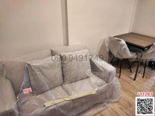 Modern living room with furniture covered in protective plastic