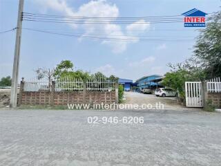 Exterior view of a property with an open gate and buildings in the background