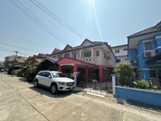 Sunny residential street view with modern townhouses and parked car