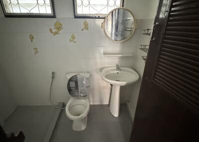 Compact residential bathroom with toilet, sink, and small mirror