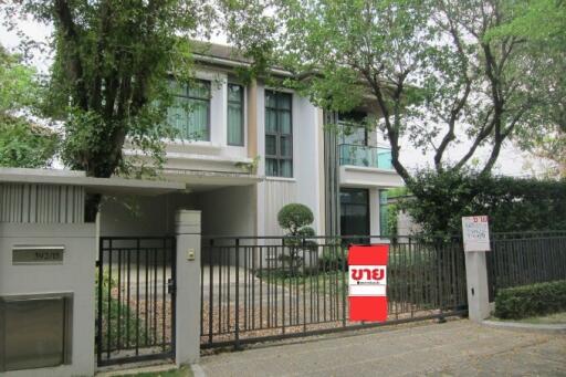 Contemporary two-story house with lush greenery and a for-sale sign