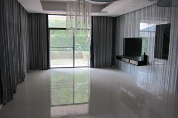 Spacious living room with a sleek modern design, large windows, and a view of the garden