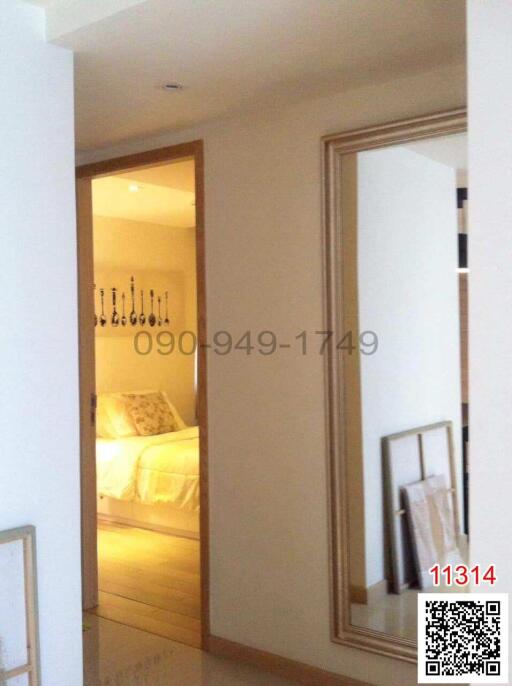 Elegant bedroom viewed through an open door with a glimpse of a stylish chandelier and modern decor