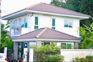 Exterior view of a modern two-story house with a tiled roof and landscaped surroundings