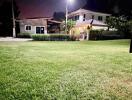 Night view of a modern two-story house with lush green lawn