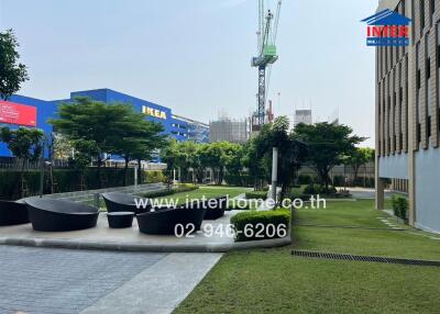 Spacious outdoor common area with landscaping and seating near residential buildings