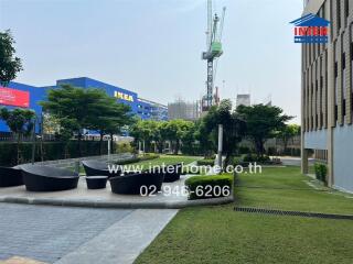 Spacious outdoor common area with landscaping and seating near residential buildings