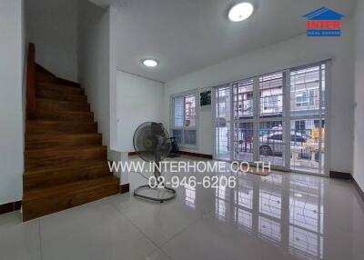 Spacious well-lit living room with wooden staircase and large windows