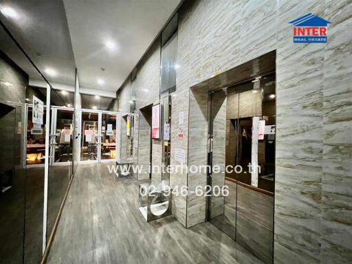 Modern building lobby with elegant stone wall design and multiple mirrored surfaces
