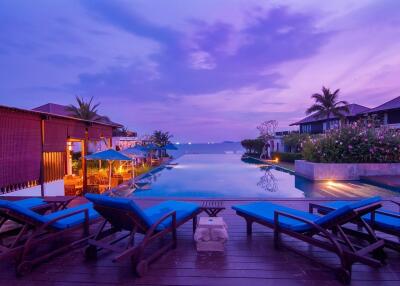 Luxurious resort pool area at dusk with lounge chairs and waterfront view