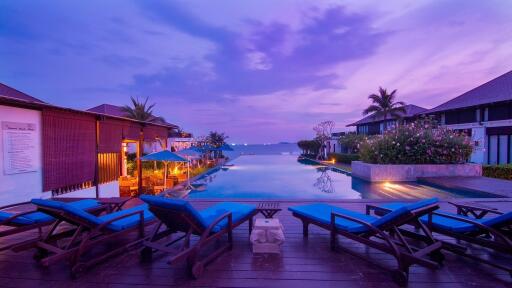 Luxurious resort pool area at dusk with lounge chairs and waterfront view