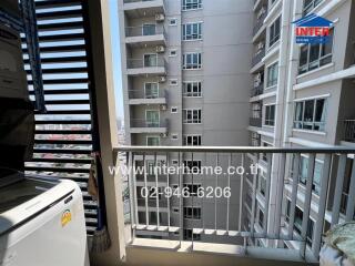 Apartment balcony overlooking other building units with washing machine and sunny city view