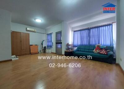 Spacious living room with wooden flooring, large sofa, and ample natural light